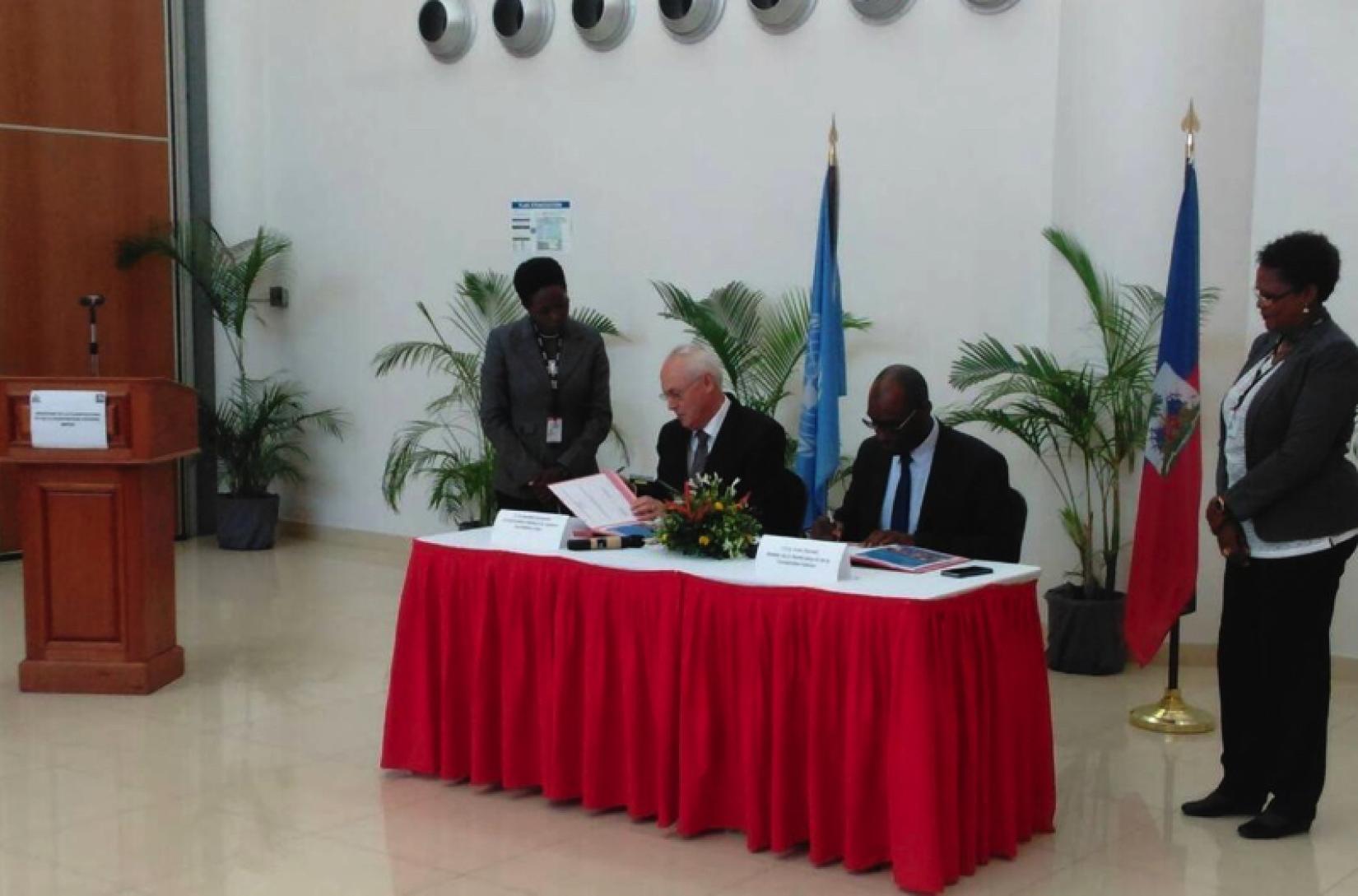 Le ministre de la Planification et de la Coopération externe, Me Aviol, et le Représentant spécial adjoint du Secrétaire général, Coordonnateur résident et Coordonnateur humanitaire de l´ONU en Haïti, M. El-Mostafa Benlamlih, Fleurant, signant le document à la Banque Centrale d´Haïti.