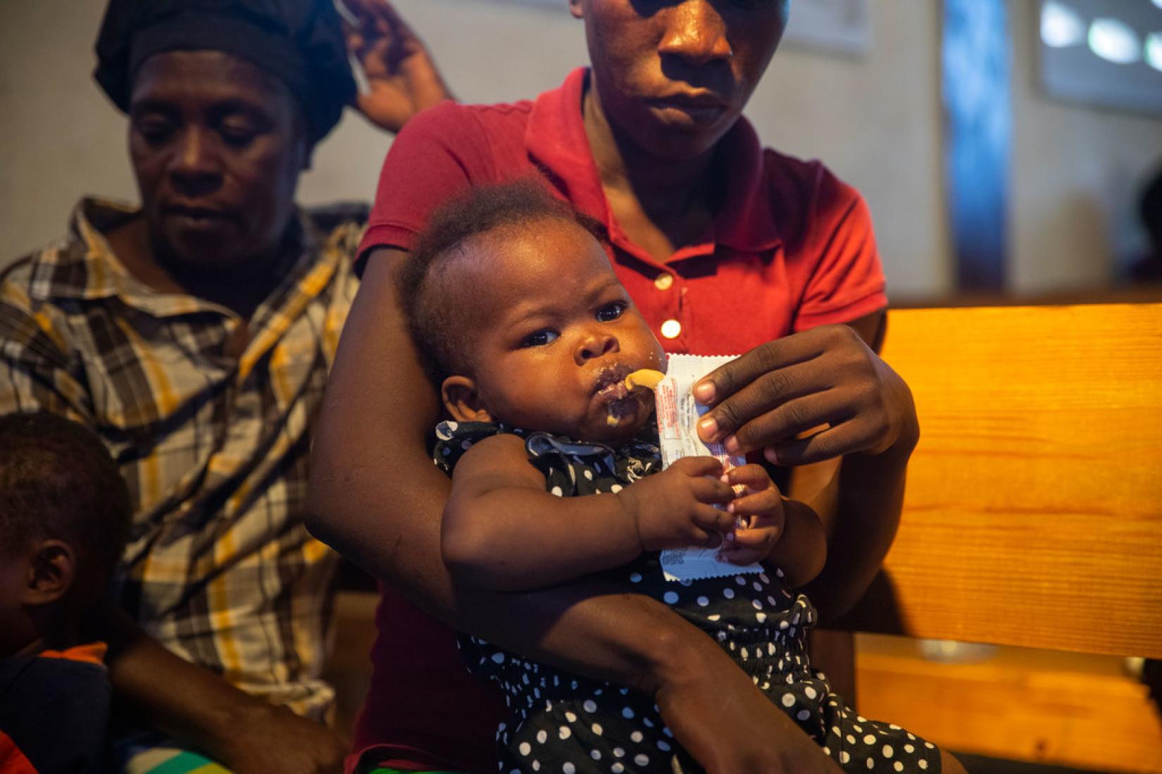 En Haïti, un enfant souffrant de malnutrition aiguë sévère mange un supplément nutritionnel.