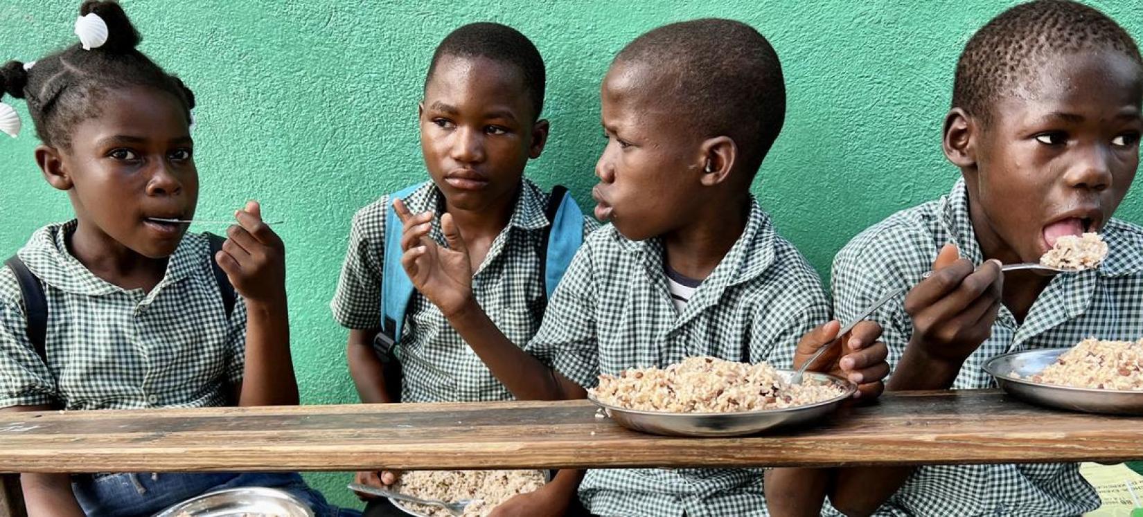Des enfants en Haïti mangent un repas fourni dans le cadre du programme d'alimentation scolaire du PAM.