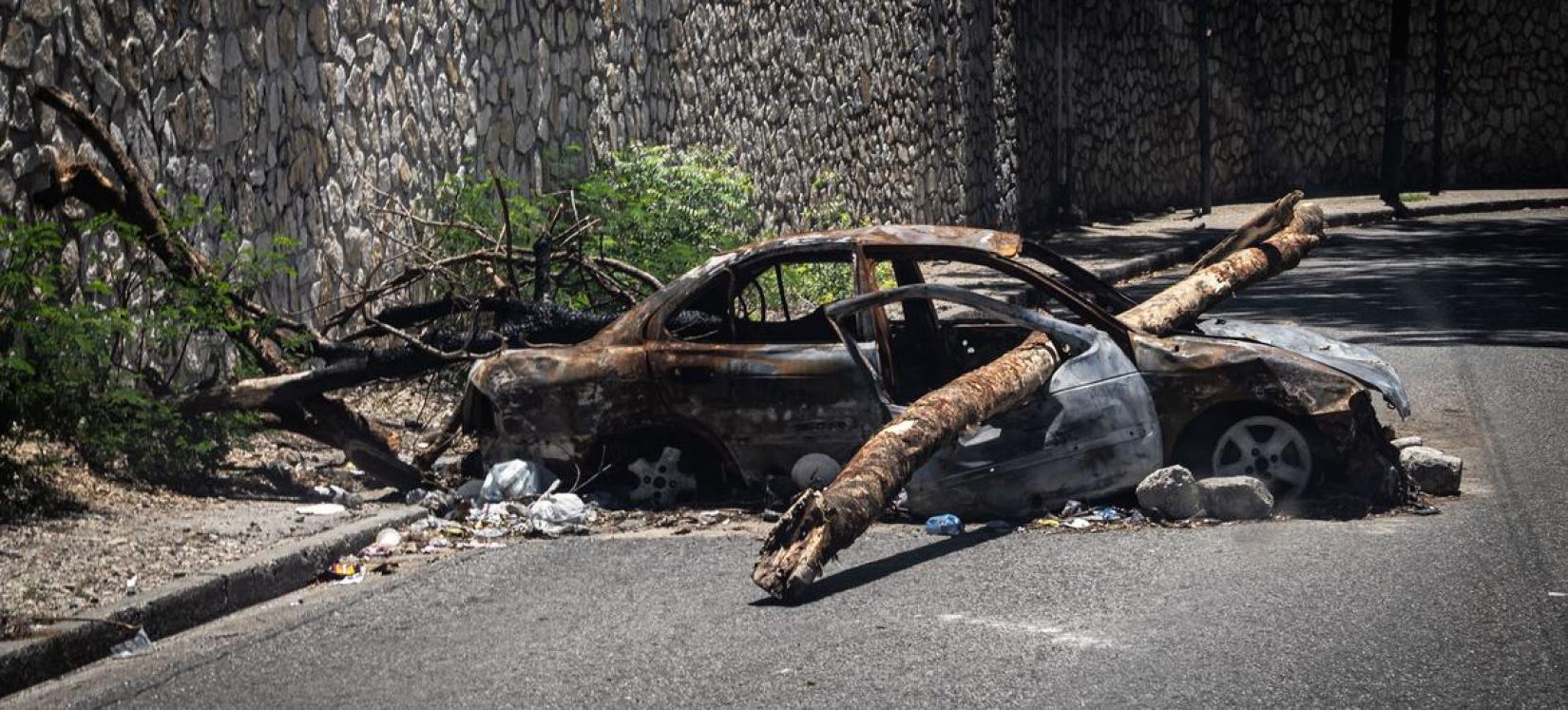 Une voiture brûlée sert de barricade dans une rue de Port-au-Prince.