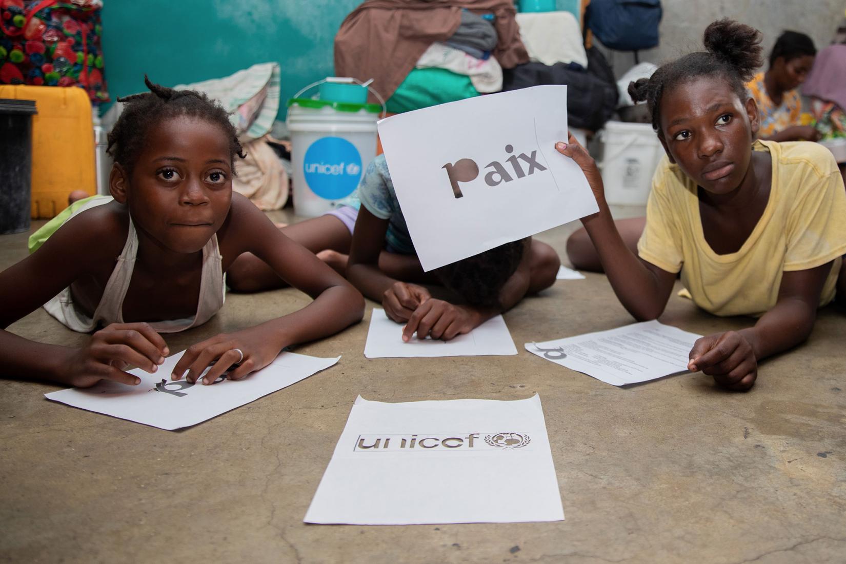 A schoolgirl in Port-au-Prince holds up a sign in French which reads 'peace'.