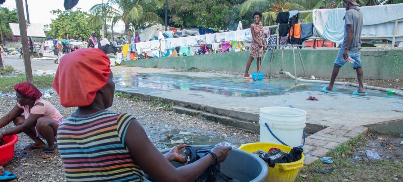 A woman displaced by Violence in the Haitian capital, Port-au-Prince washes clothes in a city park.