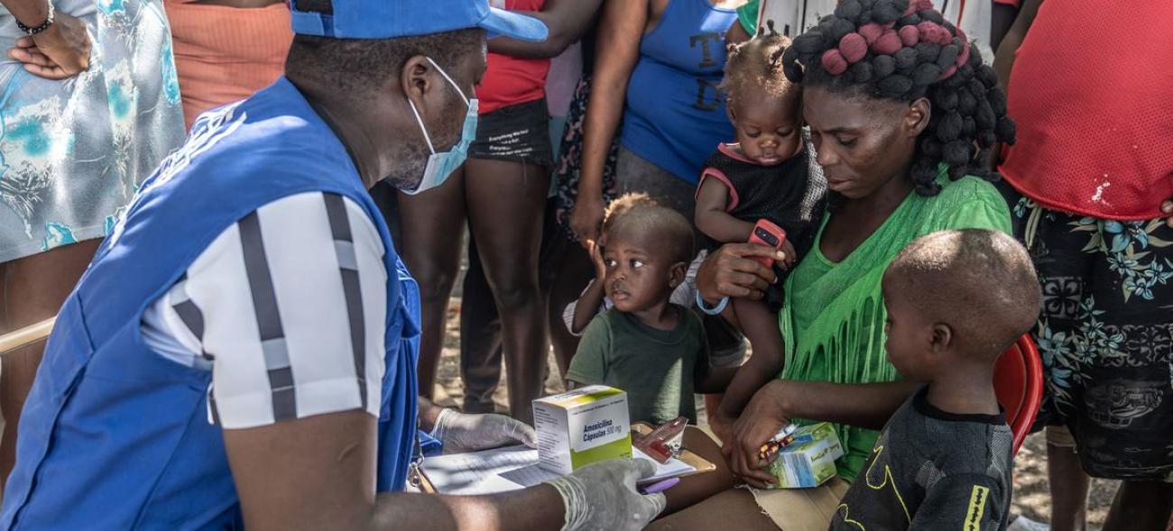 A UN staff member provides medical care to a displaced woman and children.