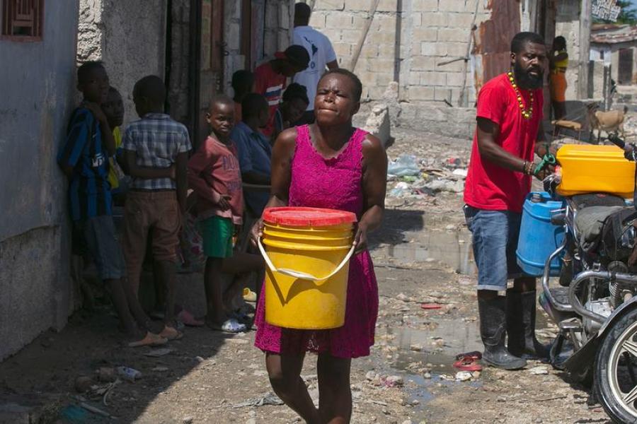A woman in Port-au-Prince, Haiti, carries water she has bought from a local trader.