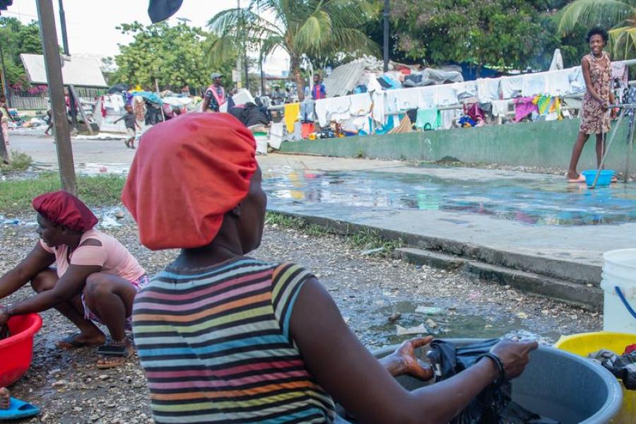 A woman displaced by Violence in the Haitian capital, Port-au-Prince washes clothes in a city park.
