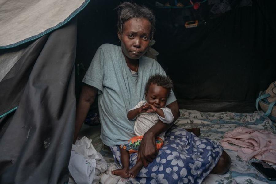 Une femme et son enfant, nés dans la tente dans laquelle ils sont assis. 600 familles vivent désormais dans une ancienne école du centre-ville de Port-au-Prince.