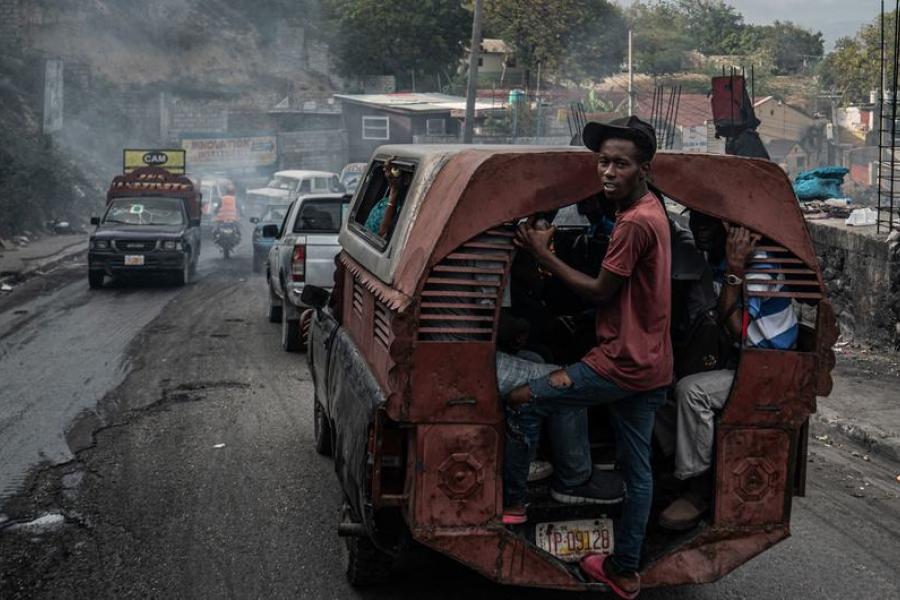 Un homme s'accroche à l'arrière d'un bus dans le quartier de Delmas, à Port-au-Prince.