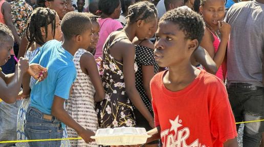 Des enfants haïtiens font la queue pour recevoir un repas chaud et de l'eau distribués par le PAM à Port-au-Prince.