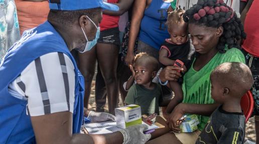 A UN staff member provides medical care to a displaced woman and children.